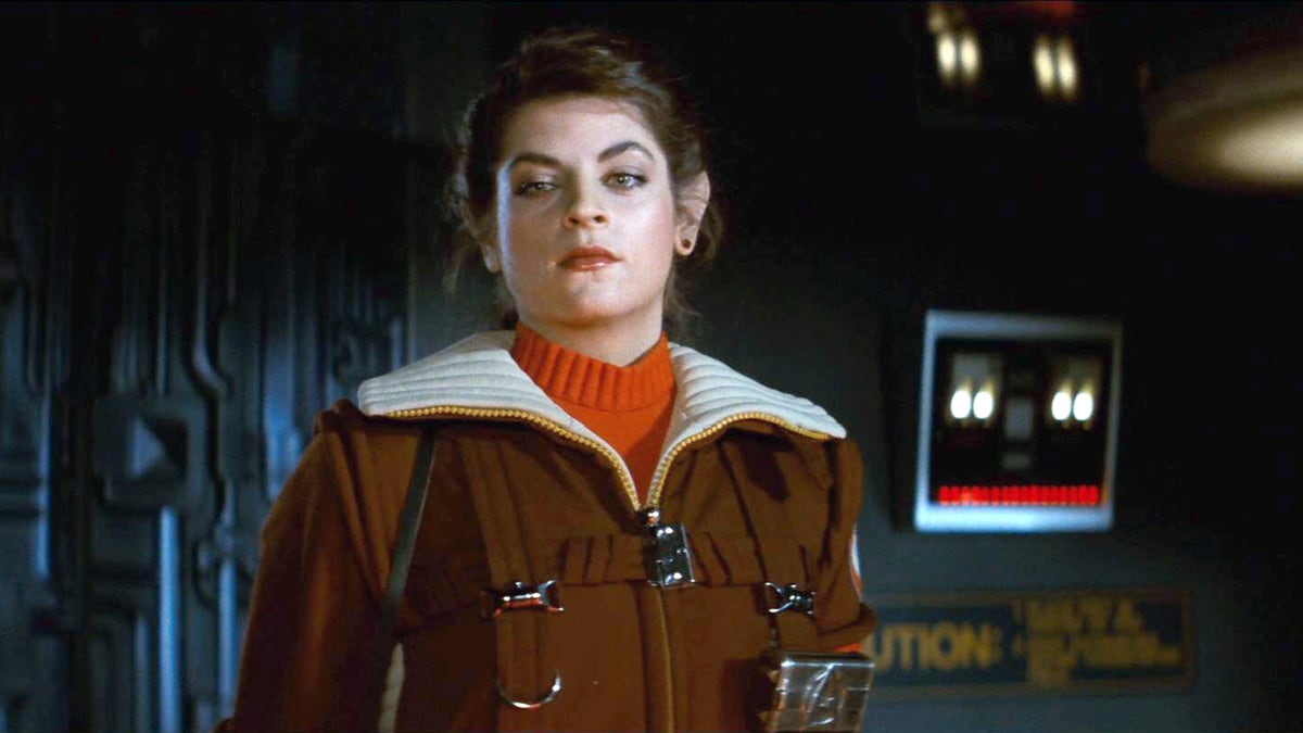 Kirstie Alley as Saavik in "Star Trek II: The Wrath of Khan" wearing a red turtleneck and brown and white coat