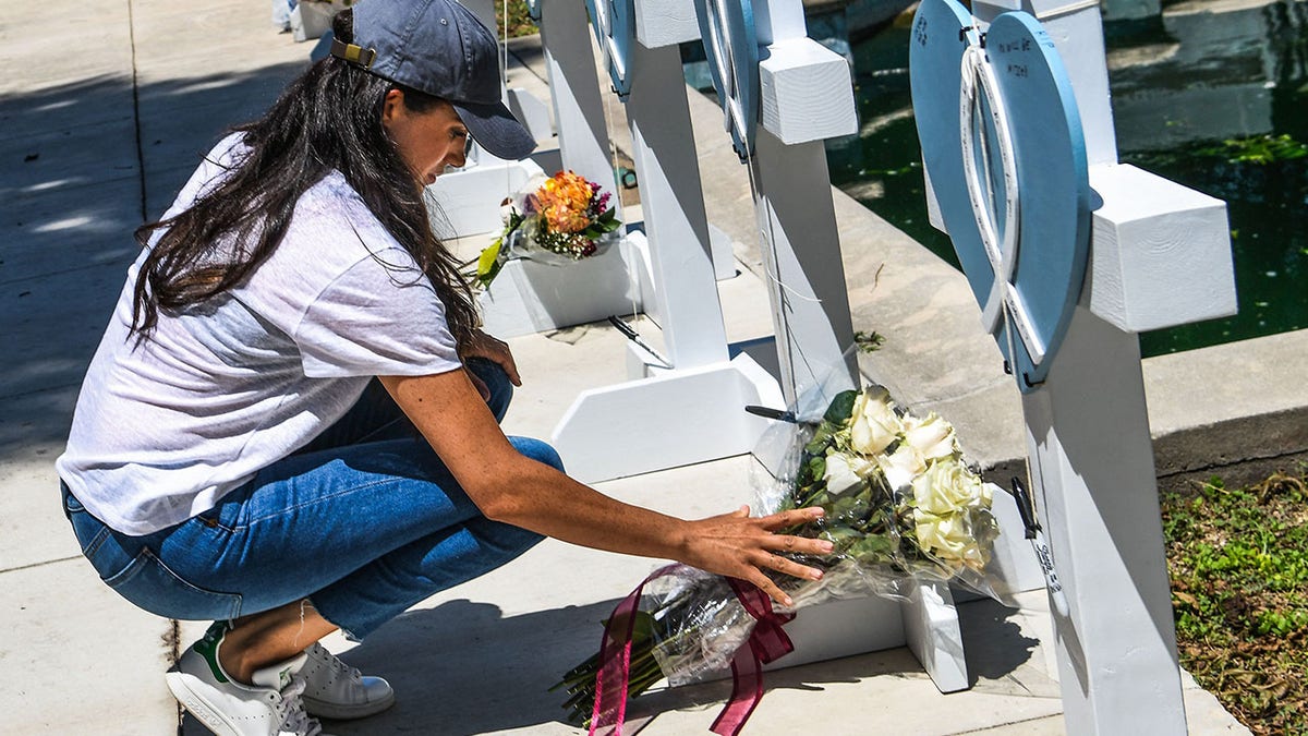 Meghan Markle places flowers at a memorial site