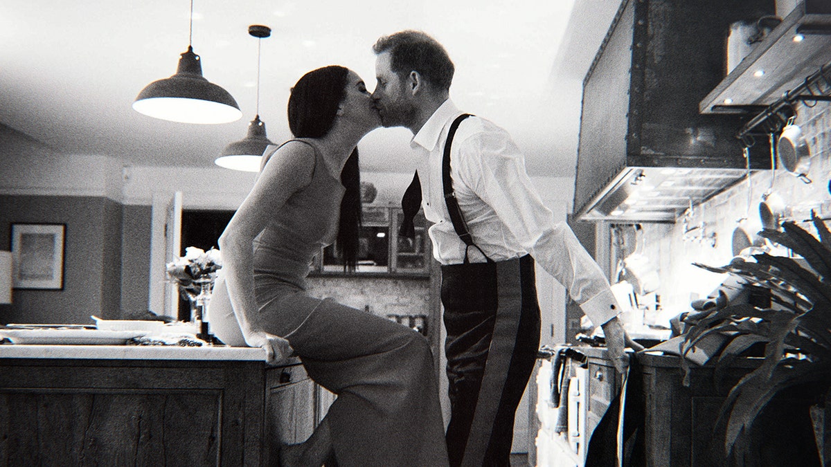 Meghan sits on the counter in her kitchen while Prince Harry kisses her in a black and white photo