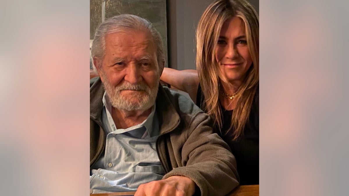John Aniston in a dark coat and light shirt poses with his daughter Jennifer Aniston in a photo