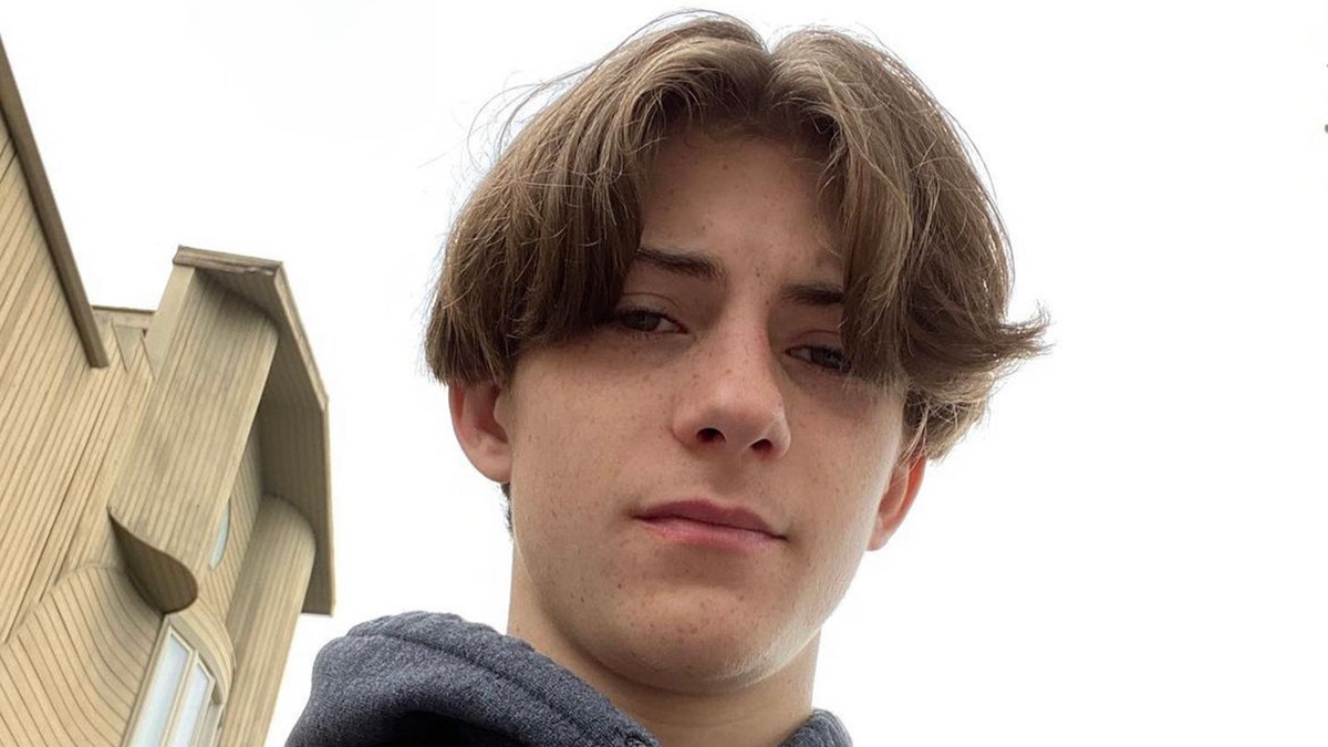 Tyler Sanders stares down at the camera in an apparent selfie with his brown hair floppy and parted in the middle
