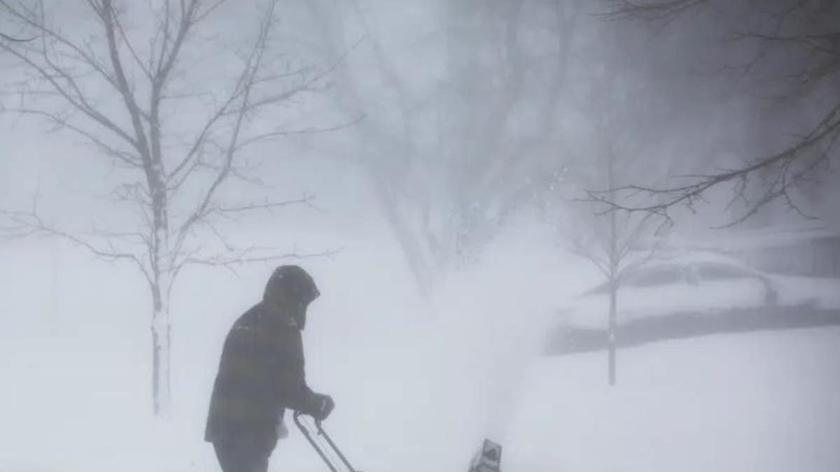 person clears snow winter storm rolls through Western New York