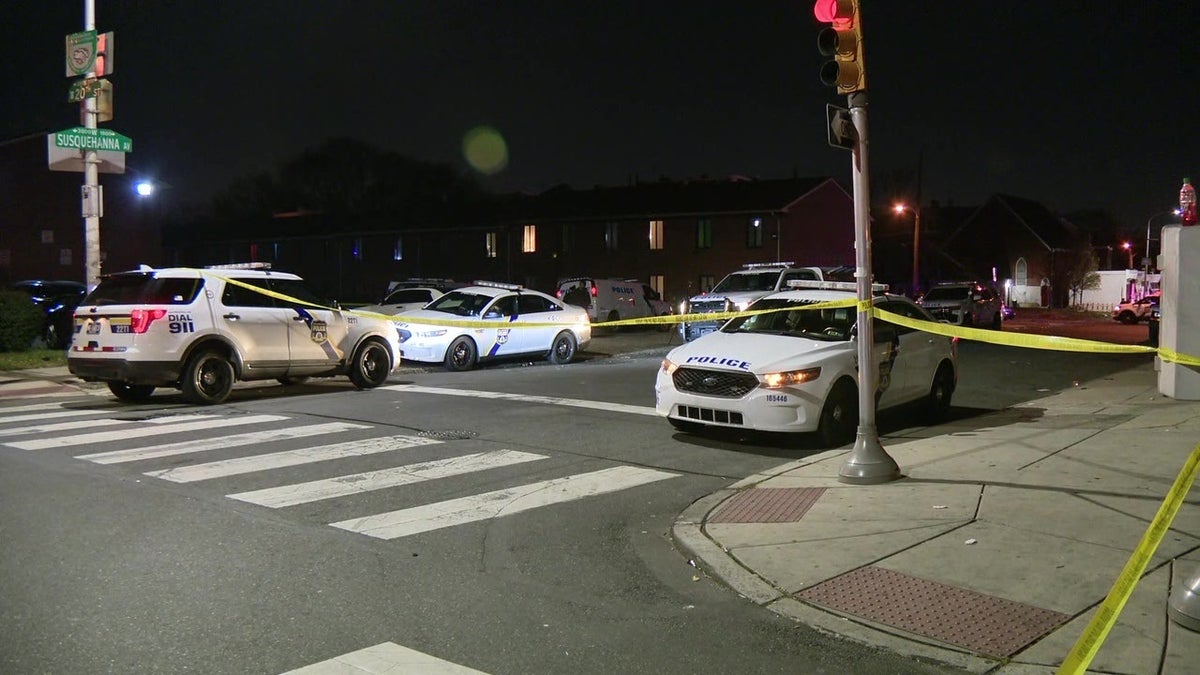 Philadelphia police cruisers, police tape at shooting scene at night