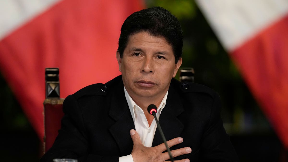 Peruvian President Pedro Castillo sitting a table with a mic