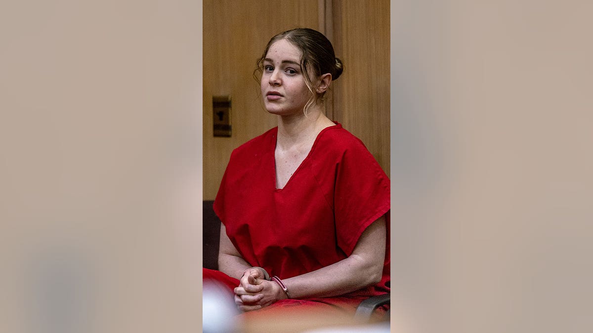 Woman in red prison garb with pink handcuffs