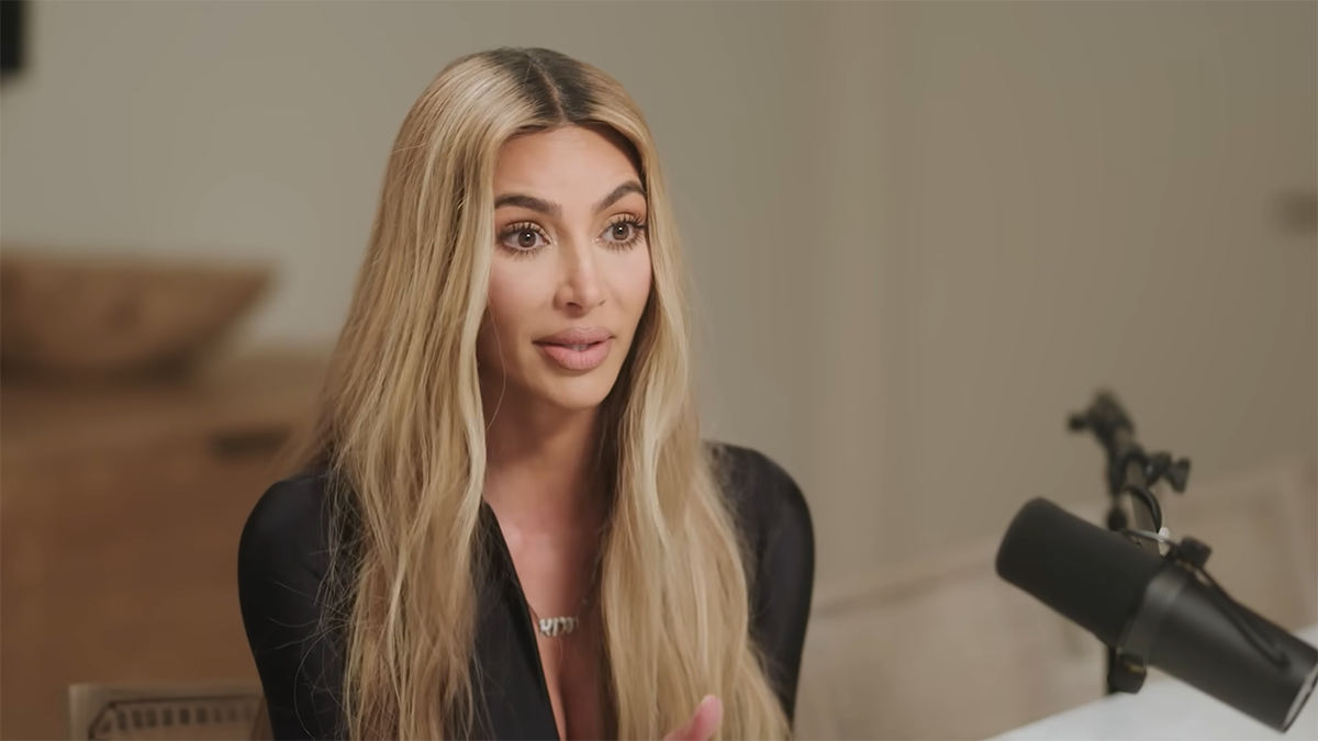 Kim Kardashian talks on the Angie Martinez podcast in a black zip up tight jacket