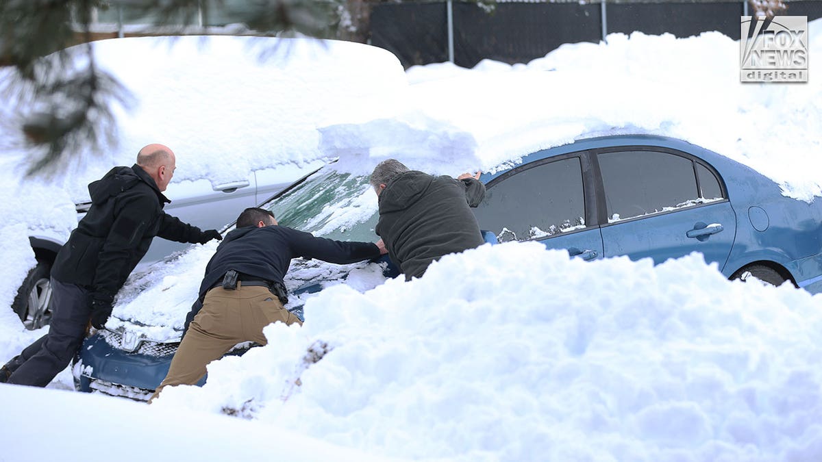 3 men dig a car out of the snow