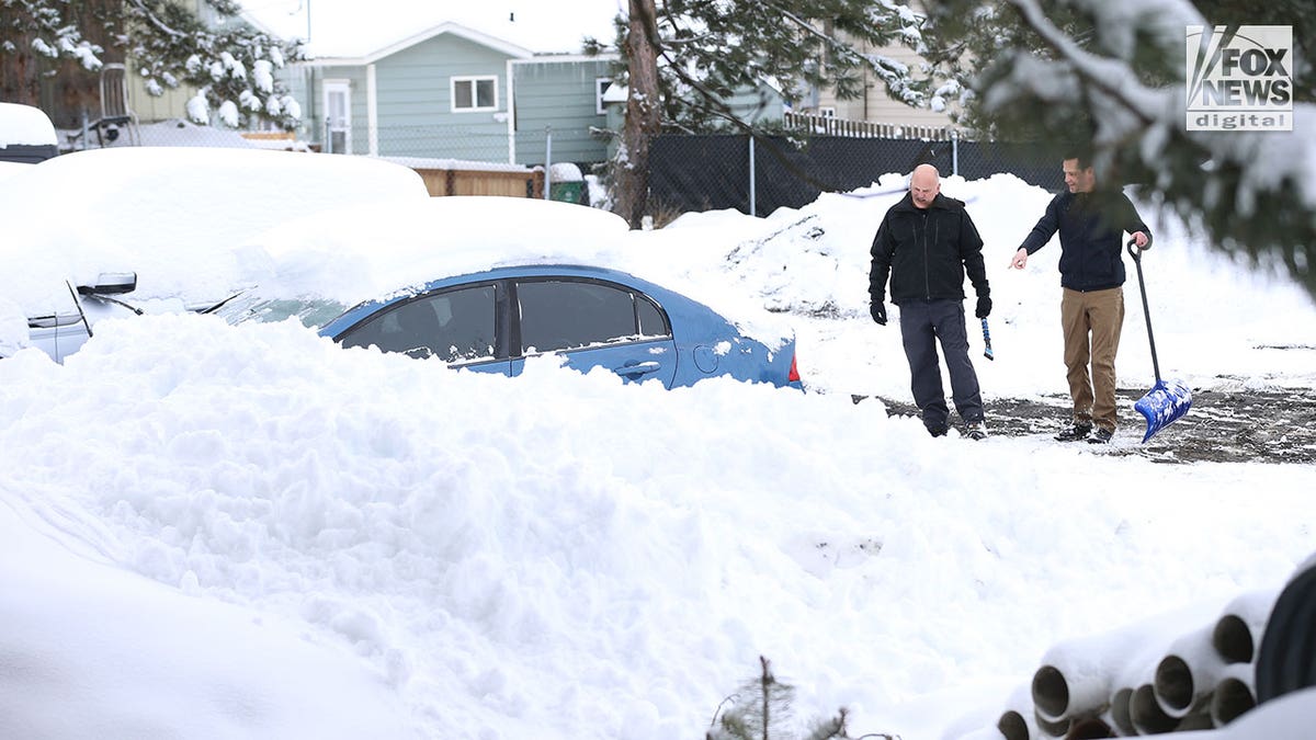 2 men prepare to dig a car out of the snow