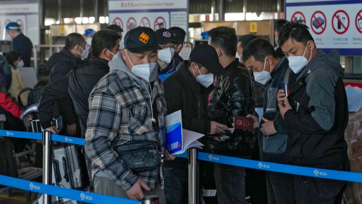 Masked travellers check their passports