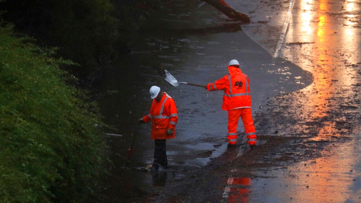 A Caltrans crew works to clear a flooded portion of an Oakland highway