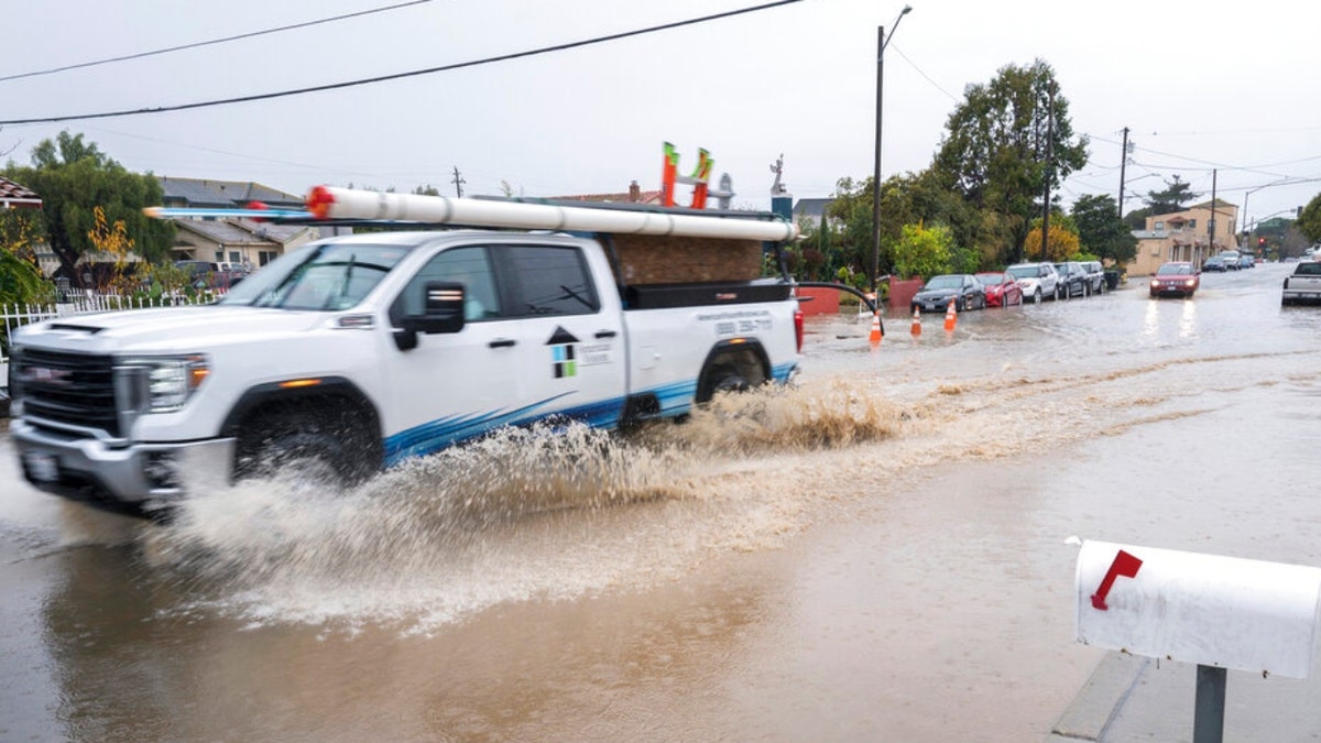 A truck drives through a flooded intersection