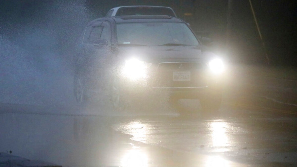 An automobile drives through a flooded portion of Mountain Boulevard