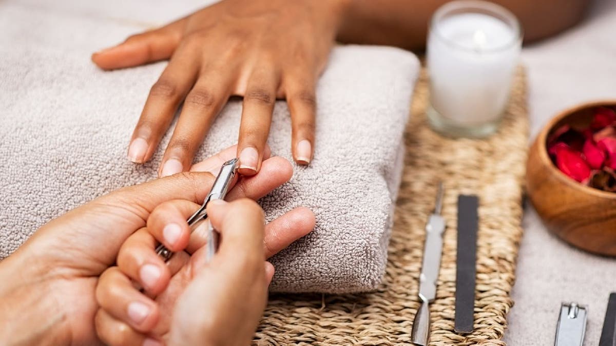 A nail technician uses a cuticle trimmer