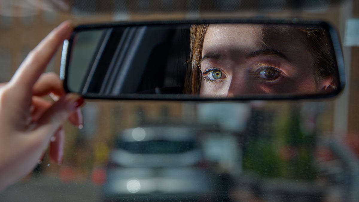 A woman who was carjacked earlier this year in Butchers Hill in Southeast Baltimore is reflected in a rearview mirror.