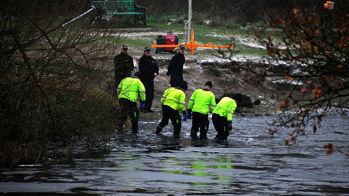 British police wade through a lake where four children fell