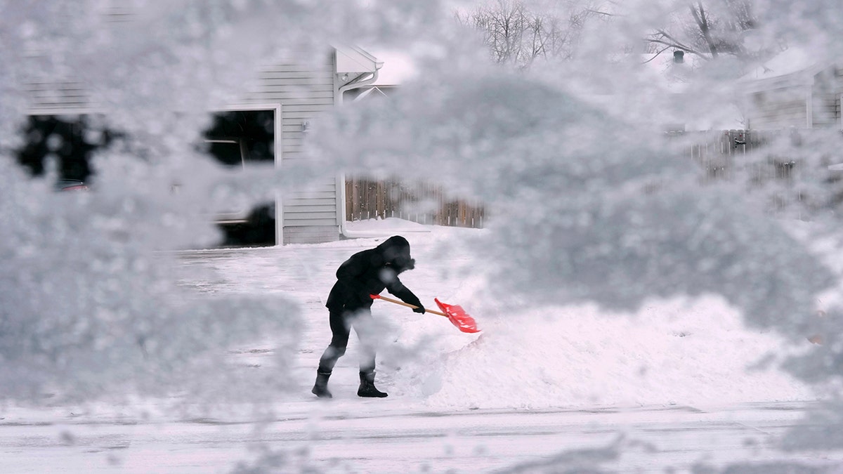 A local resident shovels snow off the end of a driveway, Thursday, Dec. 22, 2022, in Urbandale, Iowa. (AP Photo/Charlie Neibergall)