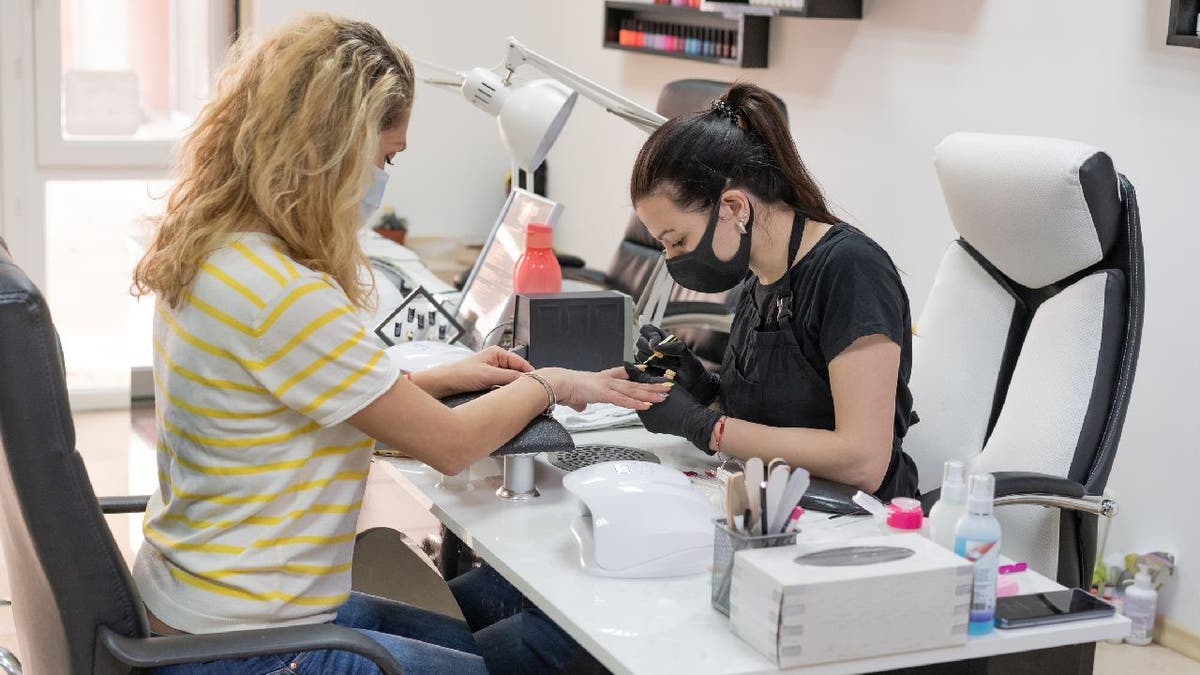 Nail technician performs a manicure service