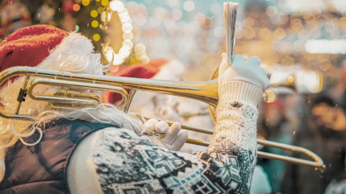 Christmas musician in Santa hat plays trombone