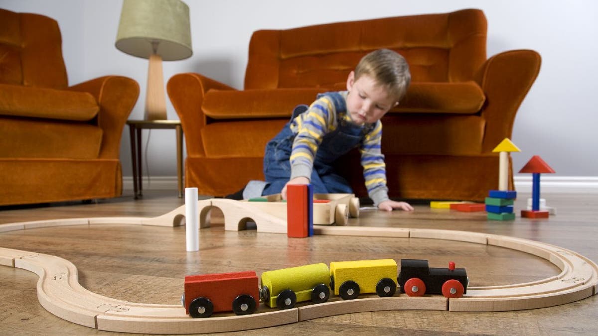 Boy plays with toy train set