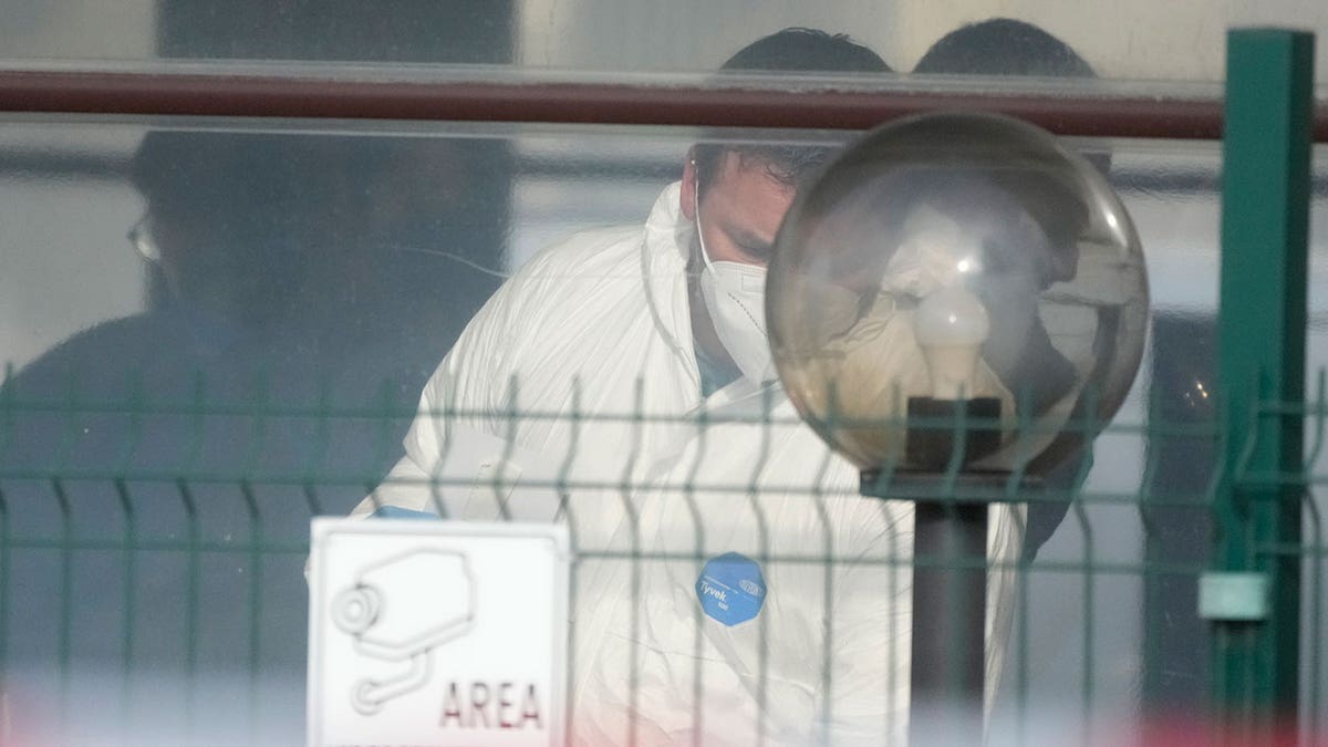 Italian forensic police are masked and work inside a building following a shooting