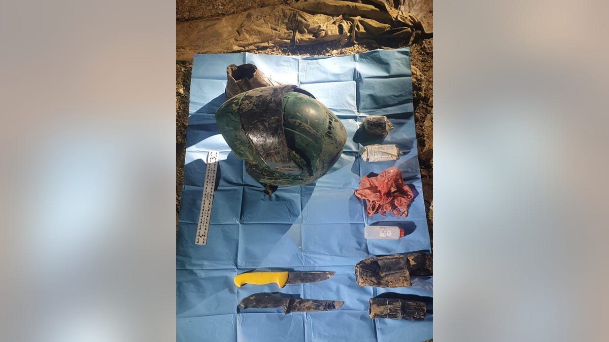 A dirty motorcycle helmet, two knives, and what appears to be explosive materials are pictured