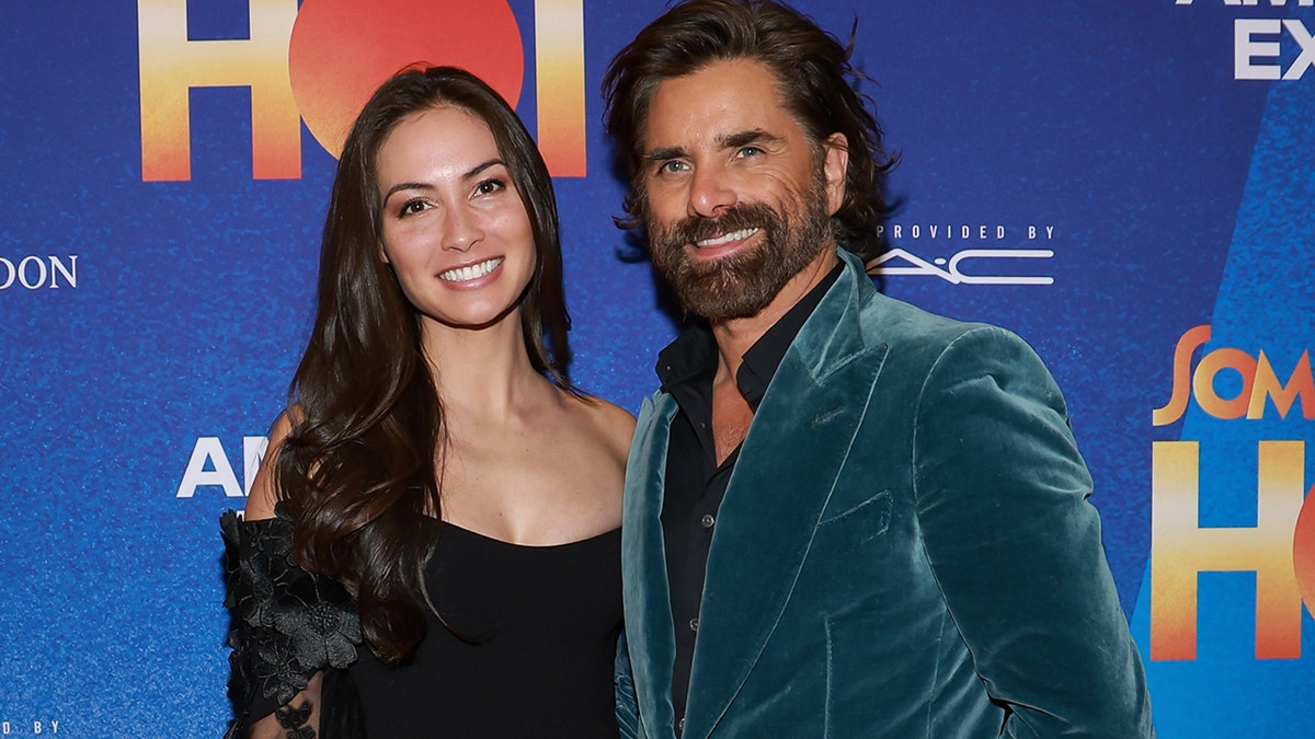 John Stamos indossa un abito sportivo in velluto sul tappeto rosso con la moglie Caitlin McHugh