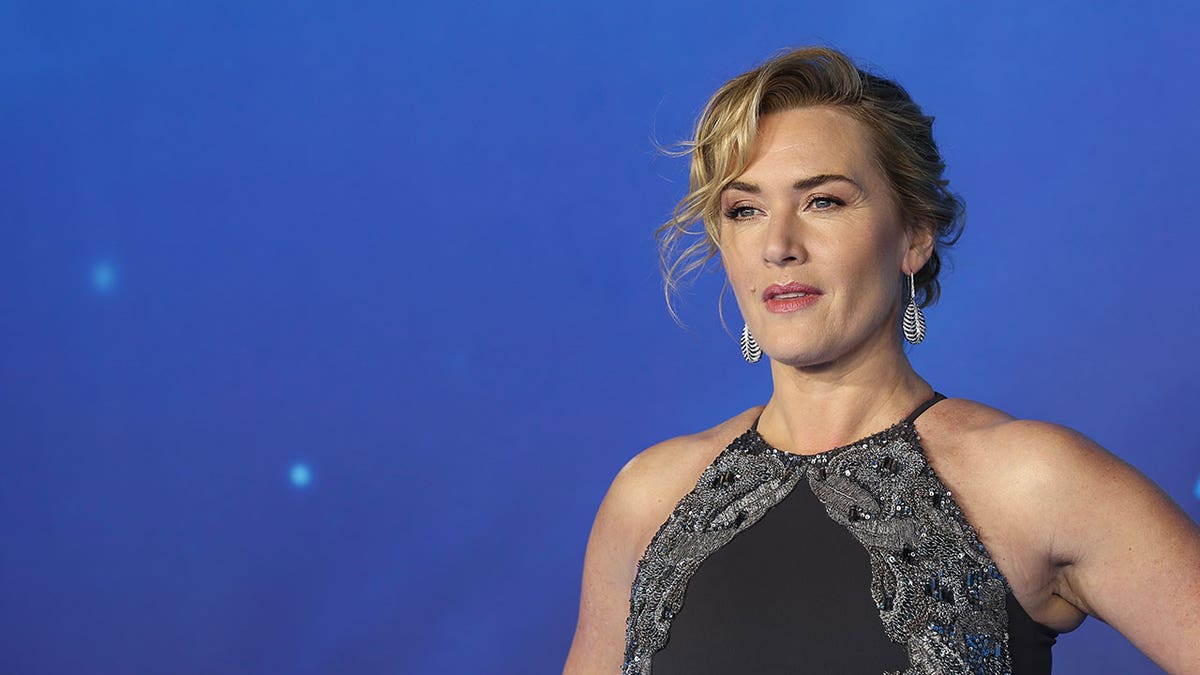Kate Winslet poses in front of a blue background during Avatar premiere