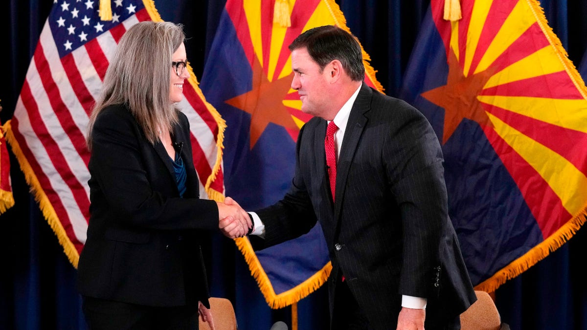 Katie Hobbs, the Democratic governor-elect and current secretary of state, left, shakes hands with Republican Gov. Doug Ducey after she signed the official certification for the Arizona general election canvass during a ceremony at the Arizona Capitol in Phoenix, Dec. 5, 2022.