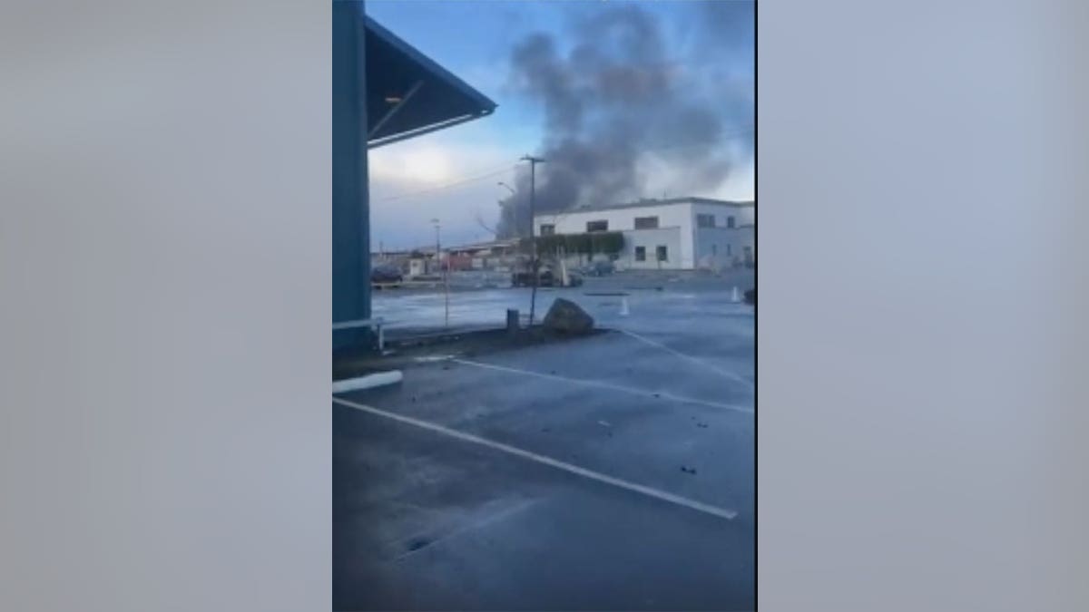 Black smoke rises into the air during a sunny day in Oakland, CA
