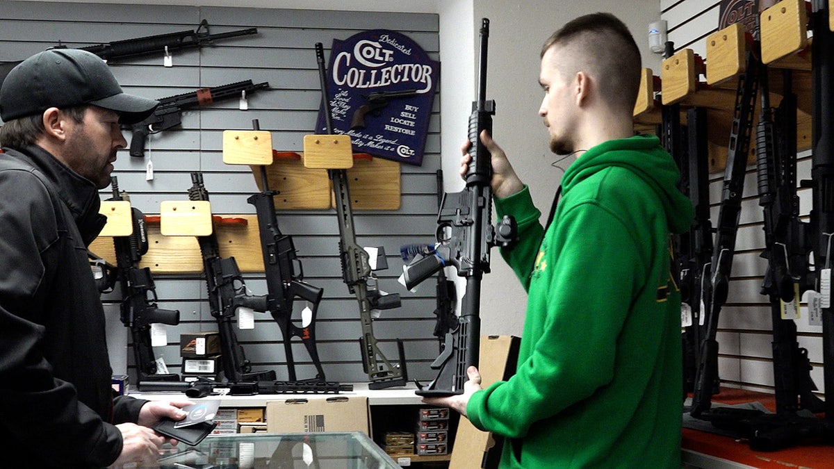 Customer looks at rifle in Oregon gun store