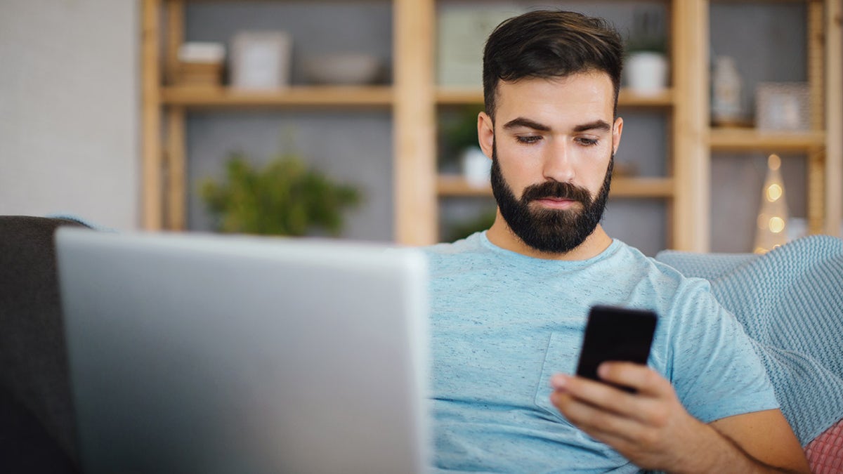 Man using laptop and on phone 