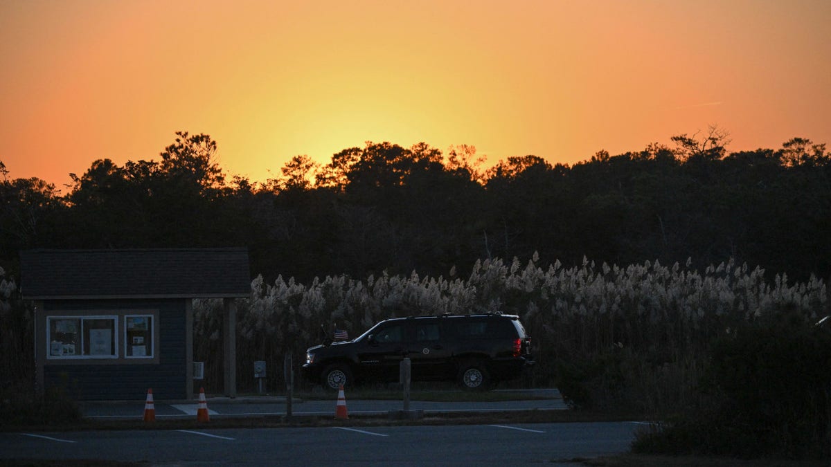 An SUV carries President Joe Biden under the setting sun to his home near Rehoboth Beach, Delaware