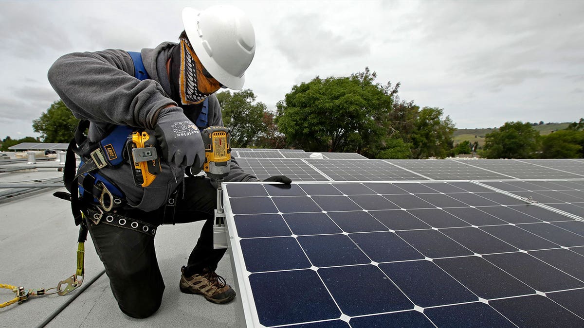 Worker installing rooftop solar panel