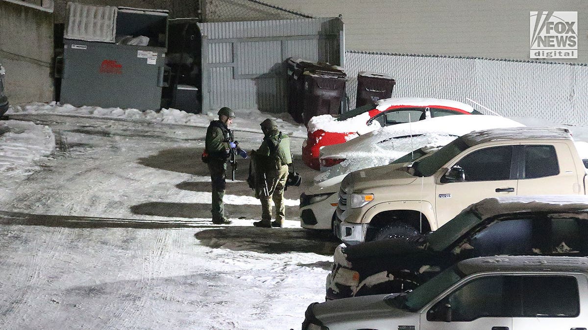 Police walk around in the snow during early morning hours