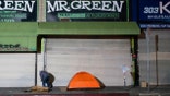 A homeless man stands next to his tent in Los Angeles, Wednesday, Dec. 14, 2022.