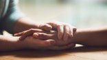 Shot of two people holding hands in comfort