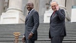 Senators Raphael Warnock and Chuck Schumer on the steps of the Capitol building