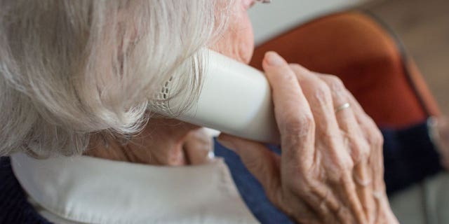 Photo of a woman on the phone possibly talking to a scammer and asking for personal information.