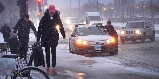 CHICAGO, ILLINOIS - DECEMBER 22: Pedestrians navigate a snow-covered sidewalk as temperatures hang in the single-digits on December 22, 2022 in Chicago, Illinois. A winter weather system bringing snow, high winds, and sub-zero temperatures has wreaked havoc on a large section of the county in front of the holidays. Strong winds are expected to combine with sub-zero temperatures tomorrow driving the wind chill in Chicago to around -40 degrees.   (Photo by Scott Olson/Getty Images)