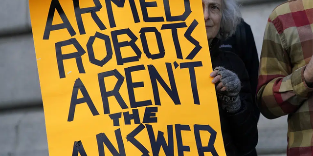 Diana Scott holds up a sign while taking part in a demonstration about the use of robots by the San Francisco Police Department outside of City Hall in San Francisco, Monday, Dec. 5, 2022.