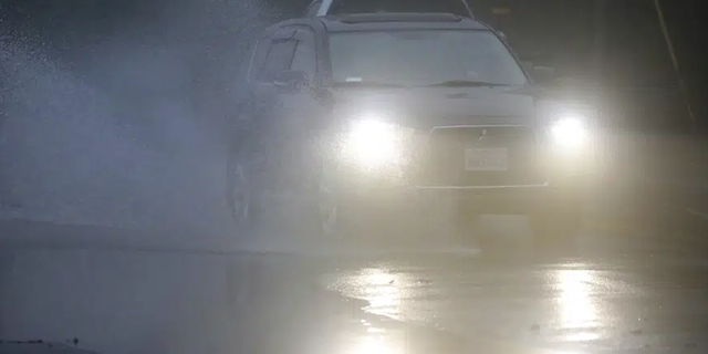 An automobile drives through a flooded portion of Mountain Boulevard in Oakland, Calif. Rain is expected across the Bay Area this week.