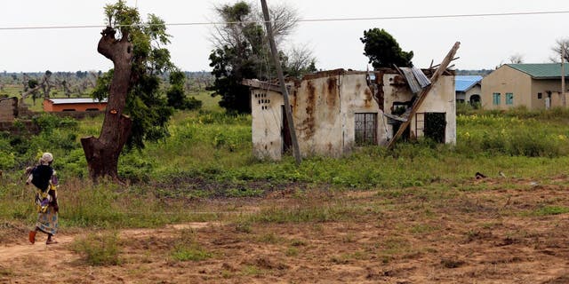 A woman walks toward a house damaged by Boko Haram militants, along the Konduga-Bama road in Bama, Borno, Nigeria