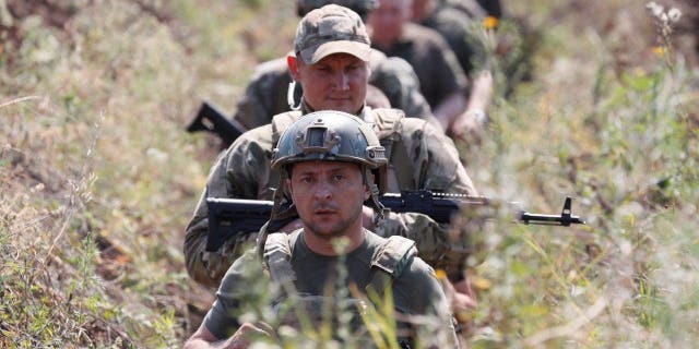 Ukraine's President Volodymyr Zelenskiy and servicemen walk in a trench near the frontline with Russian-backed separatists in Krasnohorivka in Donetsk Region, Ukraine, Aug. 7, 2020. 