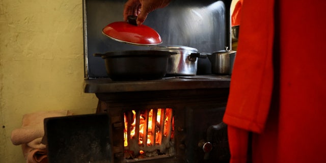 Pinkie Sebitlo cooks using a coal stove during frequent power outages from South African utility Eskom, caused by its aging coal-fired plants, in Soweto, South Africa, June 23, 2022.