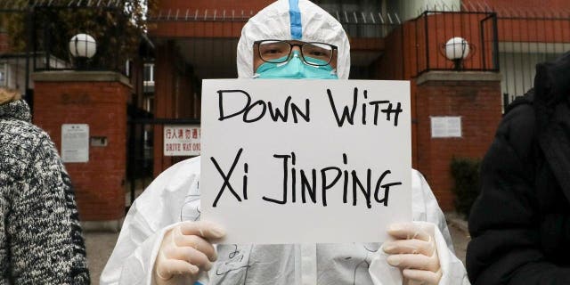 A person holds a banner during a protest in solidarity over the coronavirus disease (COVID-19) restrictions in mainland China, during a commemoration of the victims of a fire in Urumqi outside the Chinese consulate in Toronto, Ontario, Canada November 29, 2022. 