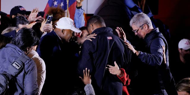 Supporters pray over U.S. Senate candidate and former football player Herschel Walker following a campaign rally in Rome, Georgia, Nov. 30, 2022. 
