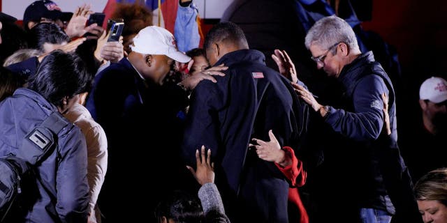 Supporters pray over U.S. Senate candidate and former football player Herschel Walker following a campaign rally in Rome, Georgia, Nov. 30, 2022.