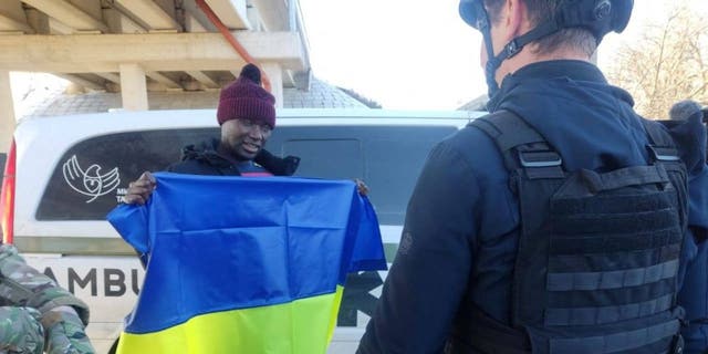 U.S. citizen Suedi Murekezi holds a Ukrainian national flag after a prisoners-of-war (POWs) swap, amid Russia's attack on Ukraine, in an unknown location, Ukraine, in this handout picture released December 14, 2022.  