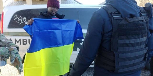 U.S. citizen Suedi Murekezi holds a Ukrainian national flag after a prisoners-of-war (POWs) swap, amid Russia's attack on Ukraine, in an unknown location, Ukraine, in this handout picture released December 14, 2022.