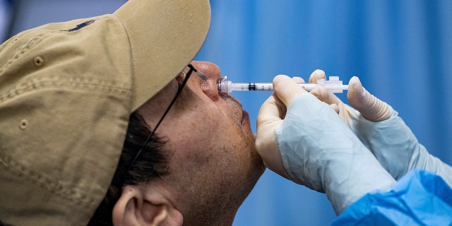A resident receives a nasal spray vaccine as a second booster dose against coronavirus disease (COVID-19), at a vaccination site in Beijing, China December 16, 2022.